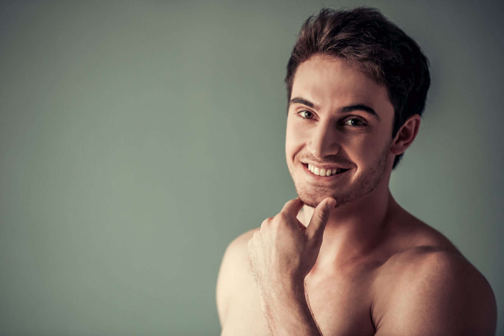 A man with no shirt is smiling for the camera.